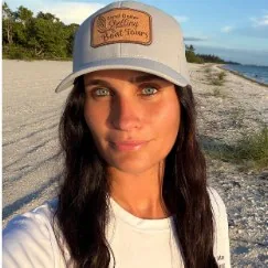First Mate Cristina in a gray cap with long dark hair on the beach
