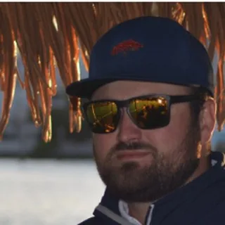 Capt. Joey Nadotti in a dark cap and gold sunglasses under the tiki roof