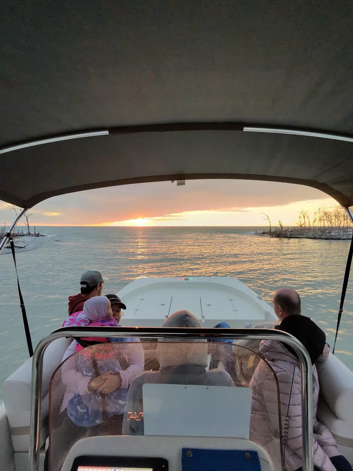 Guests on the boat watch a golden sunset over the water